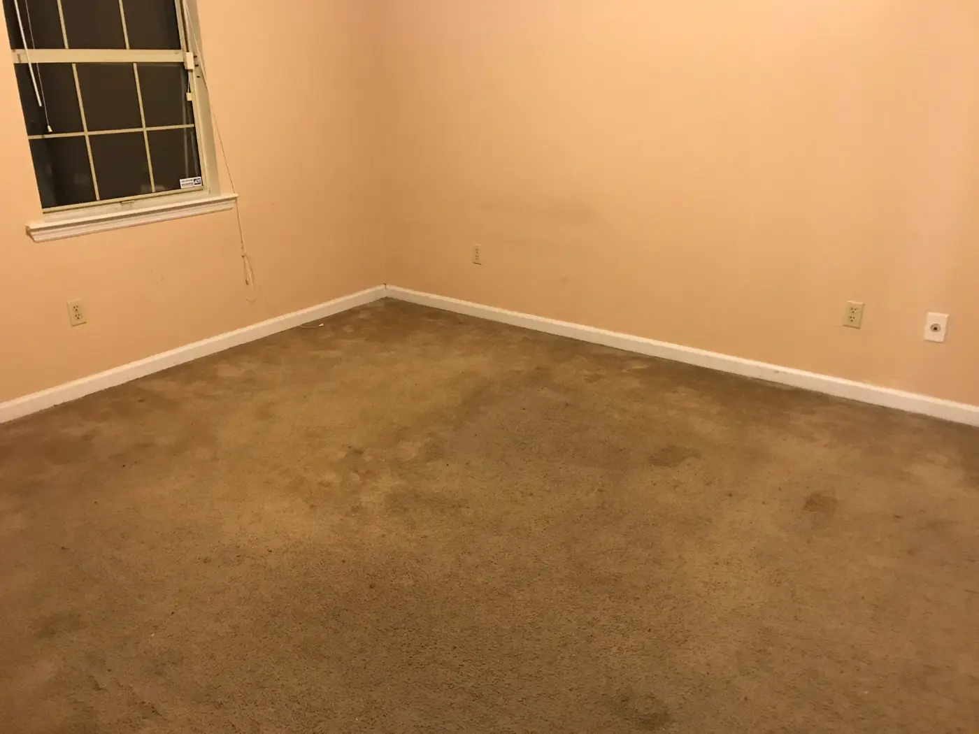 Before: a bedroom with peach walls and heavily stained brown carpet