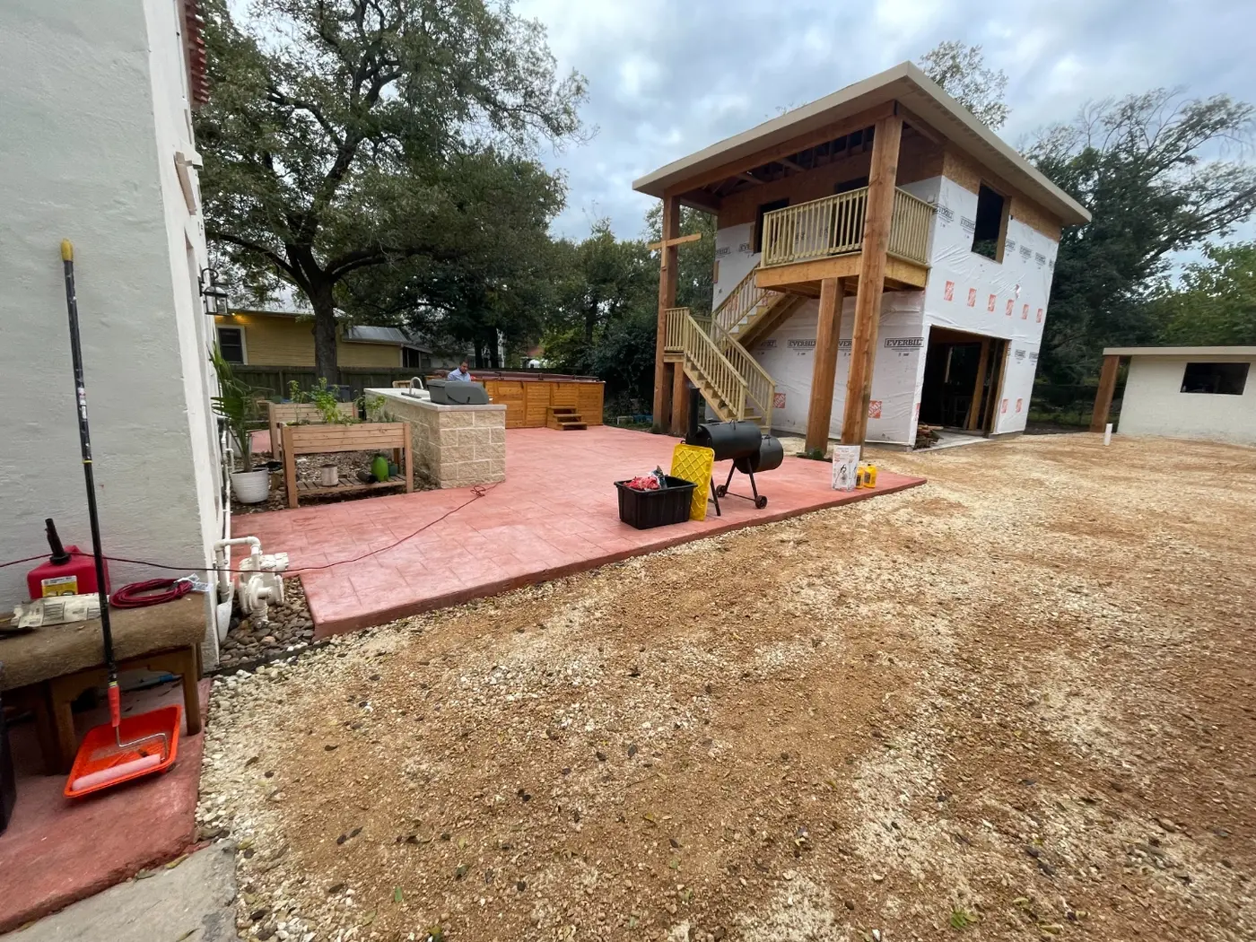 A wide shot of the finished casita with the outdoor kitchen, hot tub, and gravel drive