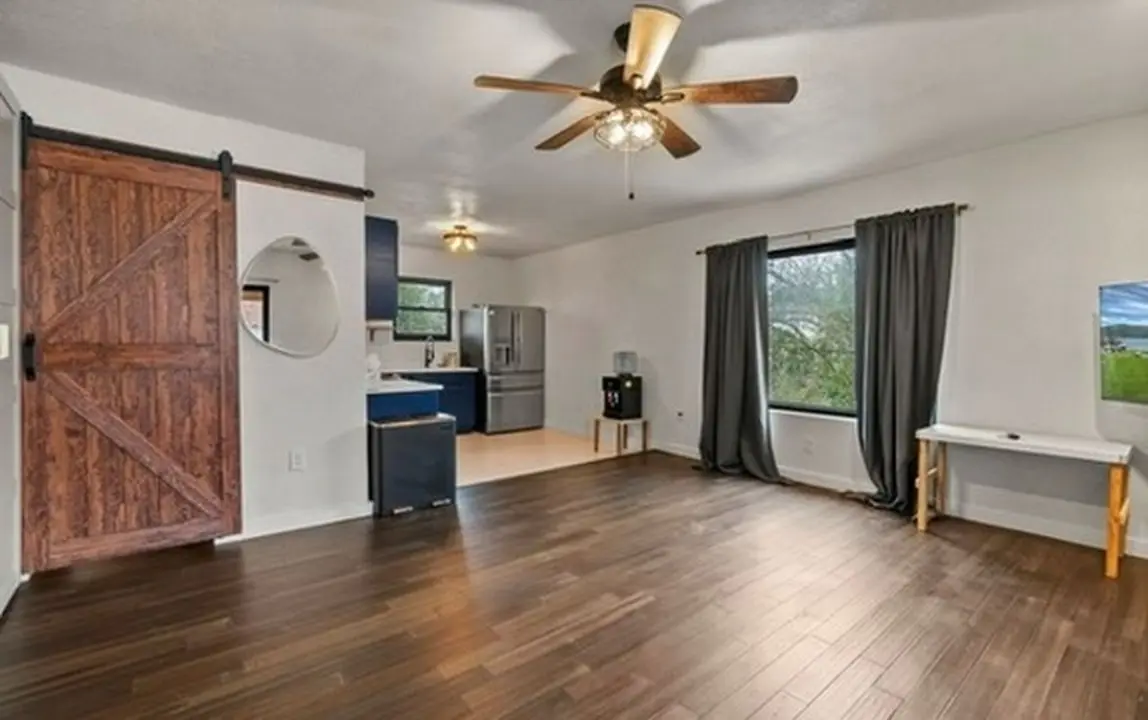 The finished guest kitchen viewed from the living room, past the barn door, with navy cabinets and a stainless refrigerator