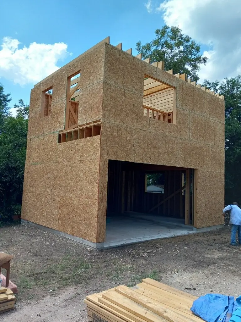 The full two-story structure framed and sheathed in OSB with the garage opening framed in
