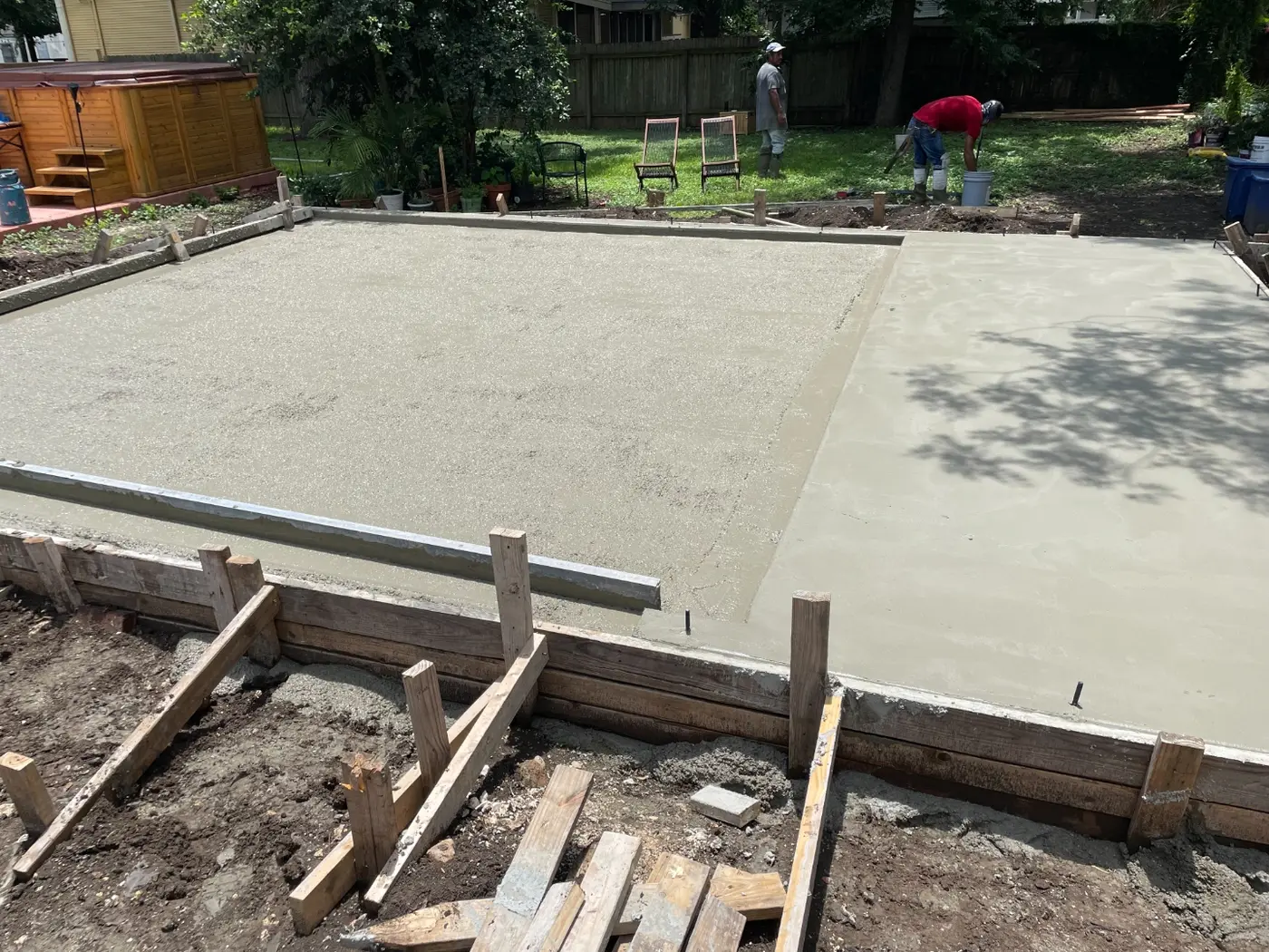 The concrete slab poured with workers finishing the surface