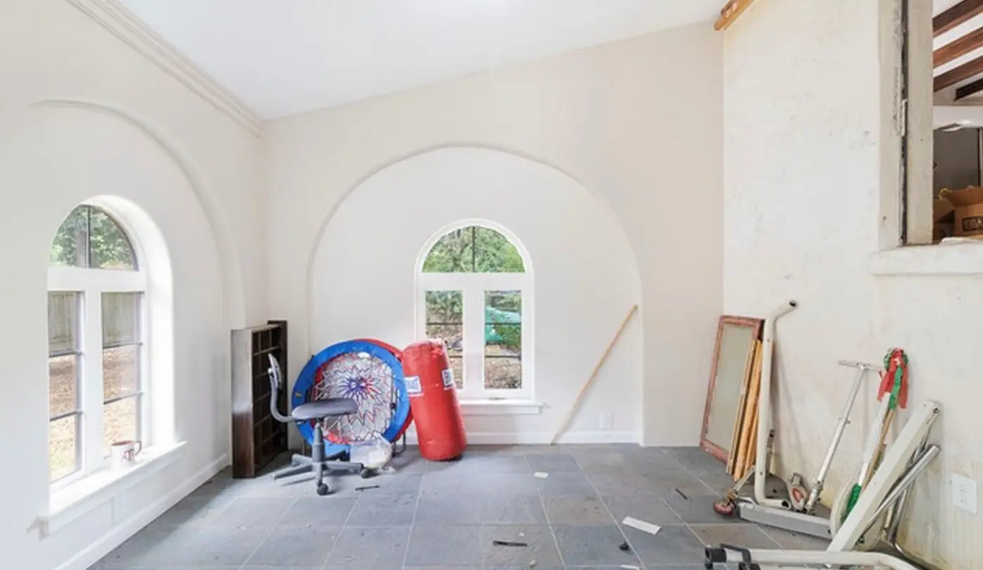 Before: a den with arched niches cluttered with exercise equipment