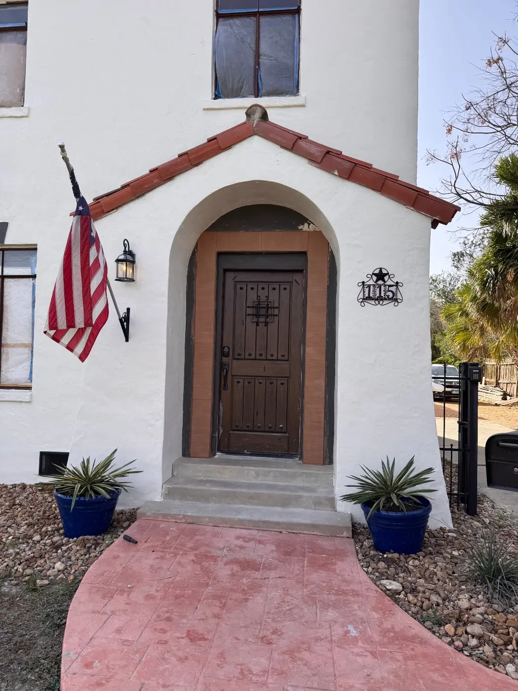 After: the same archway entry finished with a house-number plaque and an American flag