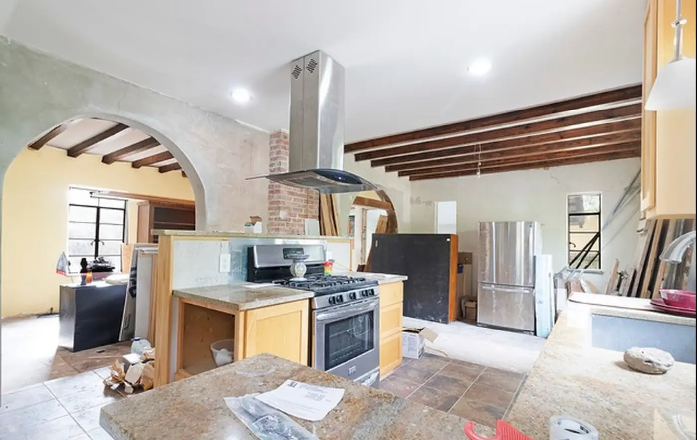 Before: the kitchen with the original cabinets, a high counter behind the stove, and the exposed backside of the brick chimney