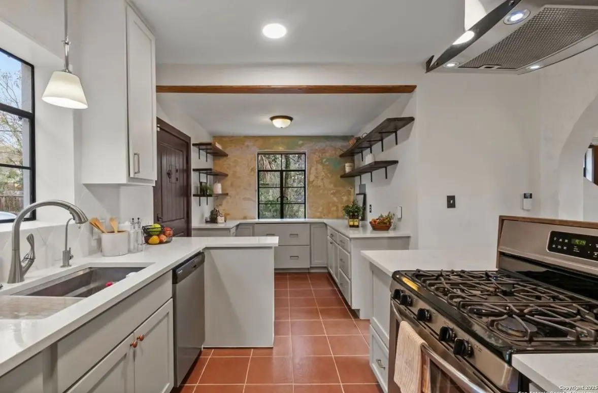 After: the same wall with gray cabinetry and the aged plaster kept as open-shelving feature