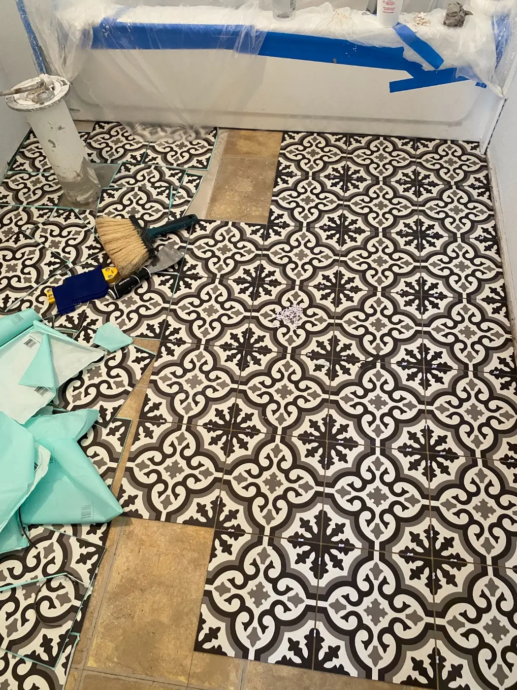 Patterned cement-look floor tile being laid in the bathroom