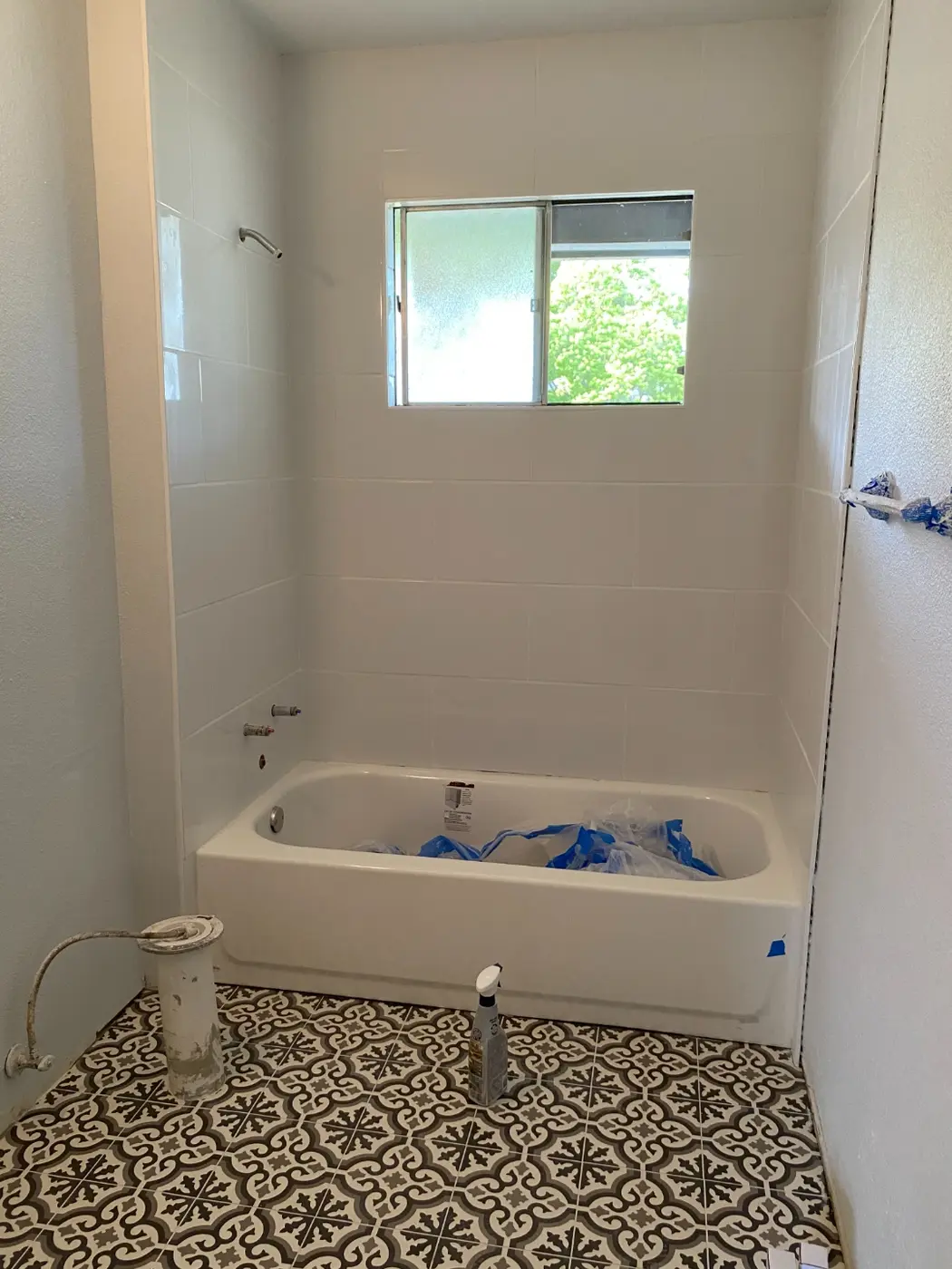 Finished white tile tub surround with the patterned floor tile installed