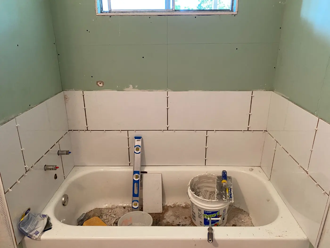Bathroom mid-renovation with tile going up around the tub
