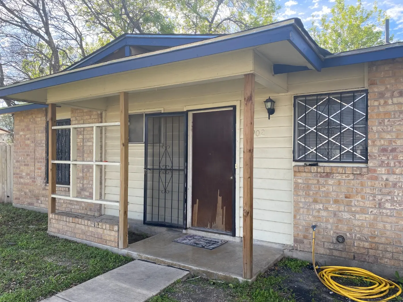 Before: the front exterior of the Martinique house with plain white brick and no landscaping