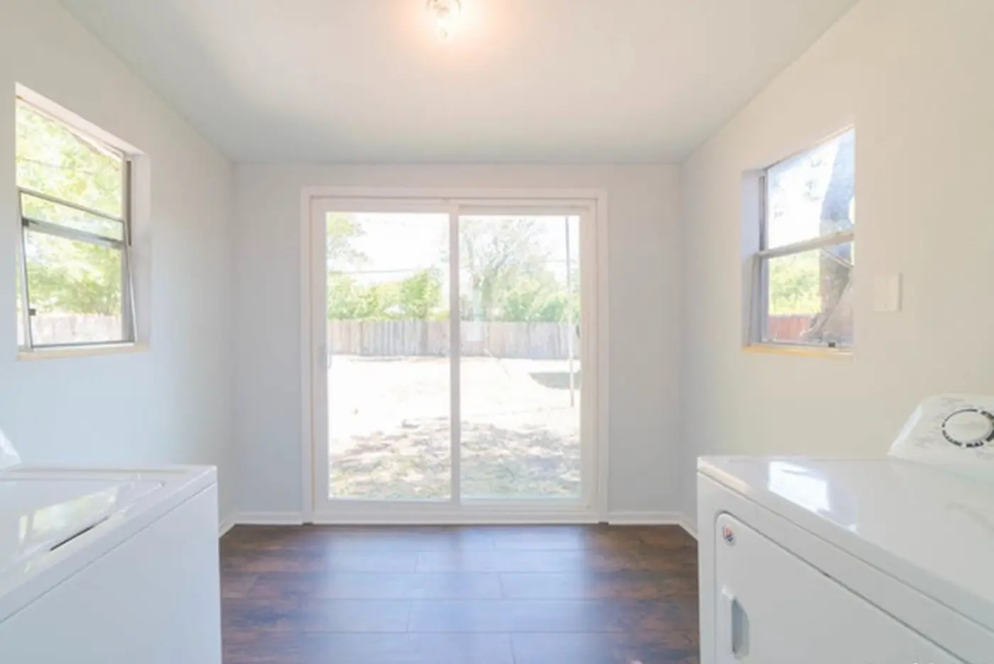After: the finished laundry room, bright and open with the sliding glass door leading to the backyard