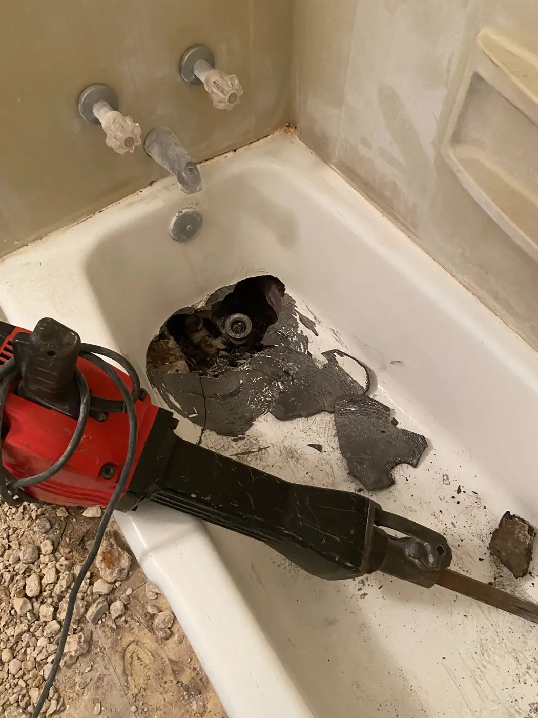 The bathtub jackhammered open, exposing the drain that had come detached from the plumbing
