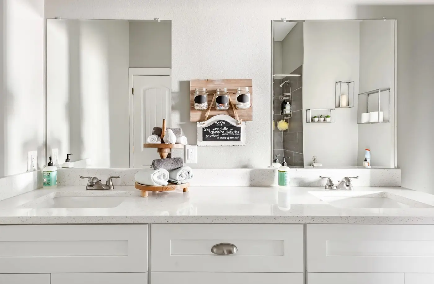 After: a bright double-vanity bathroom with quartz counters and rolled towels