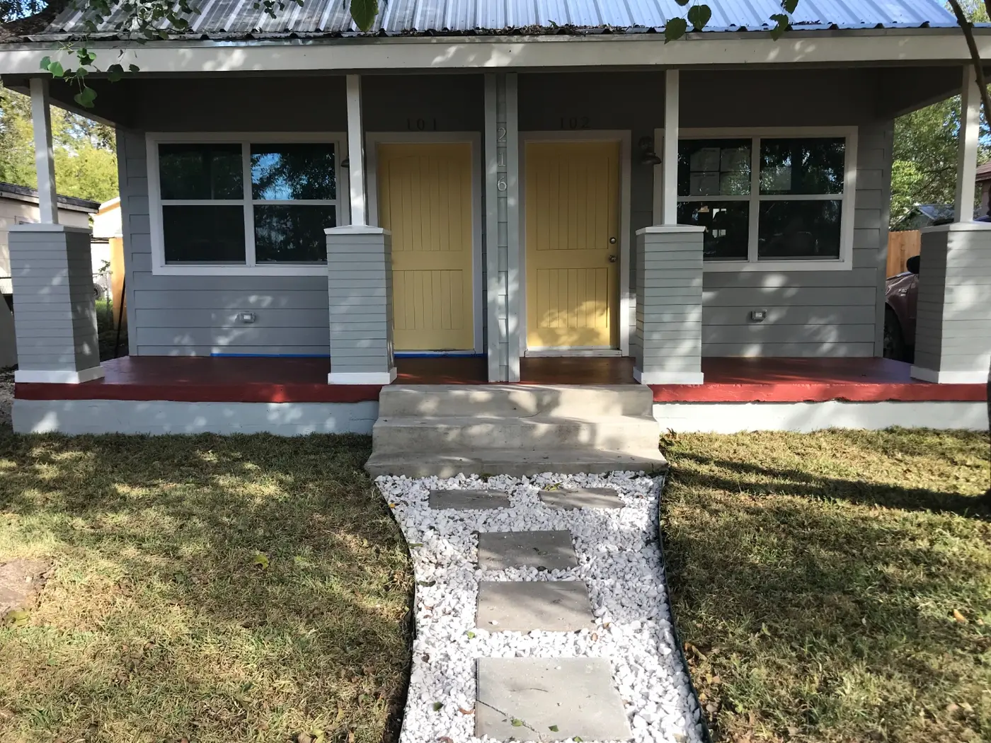 After: the finished duplex exterior, painted gray with yellow doors marked 101 and 102