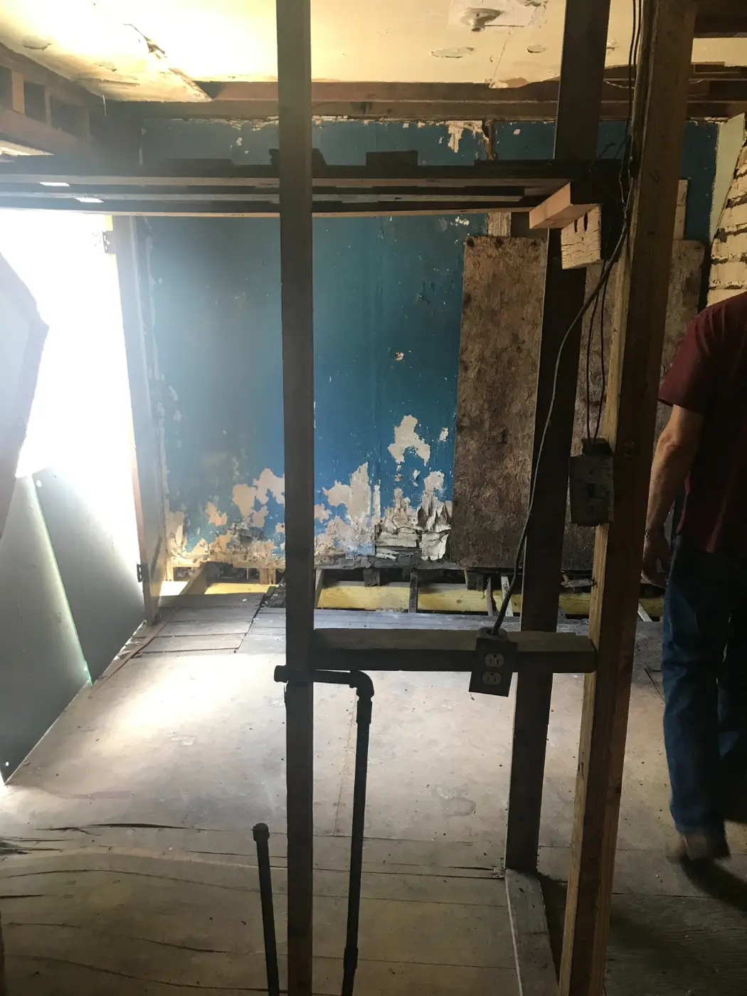 Before: an interior room stripped to studs with peeling teal paint
