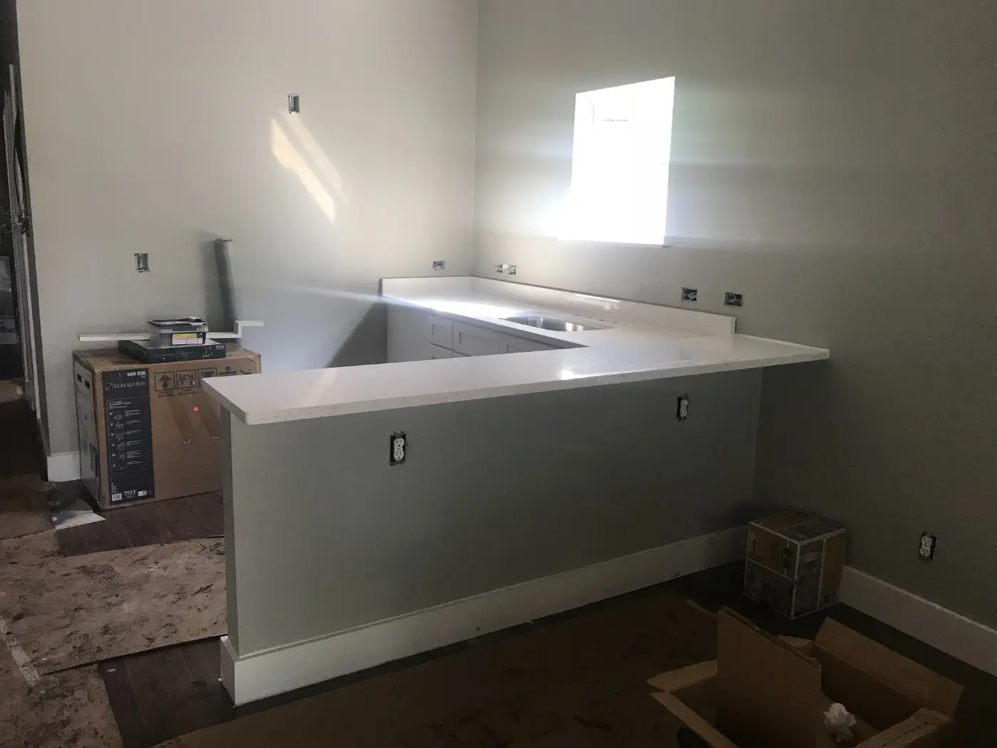 During: new quartz countertops installed over unfinished cabinets