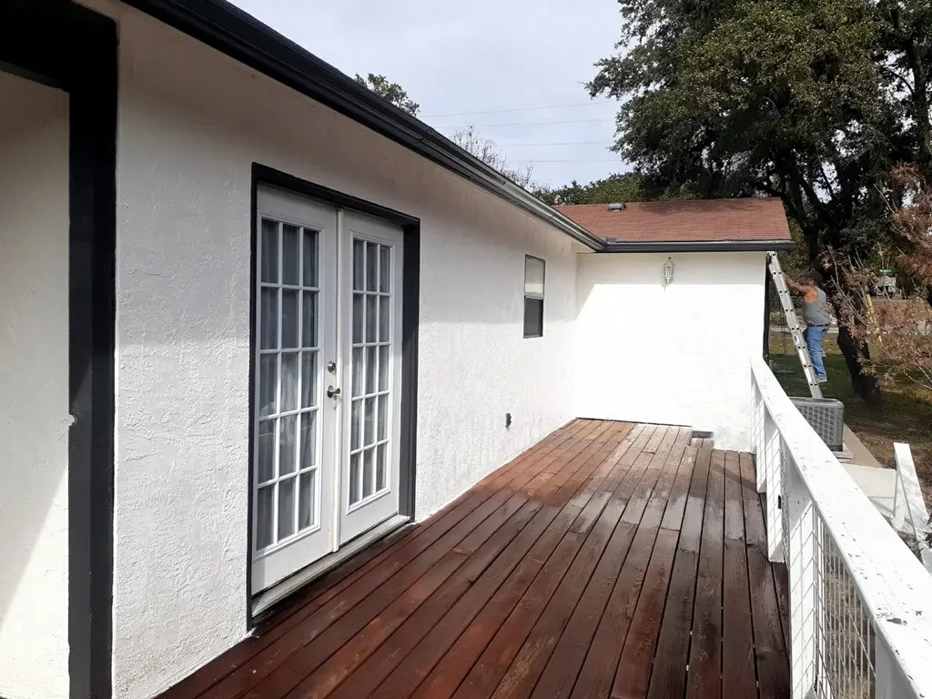 Repainting the exterior trim while the newly restained deck dries below