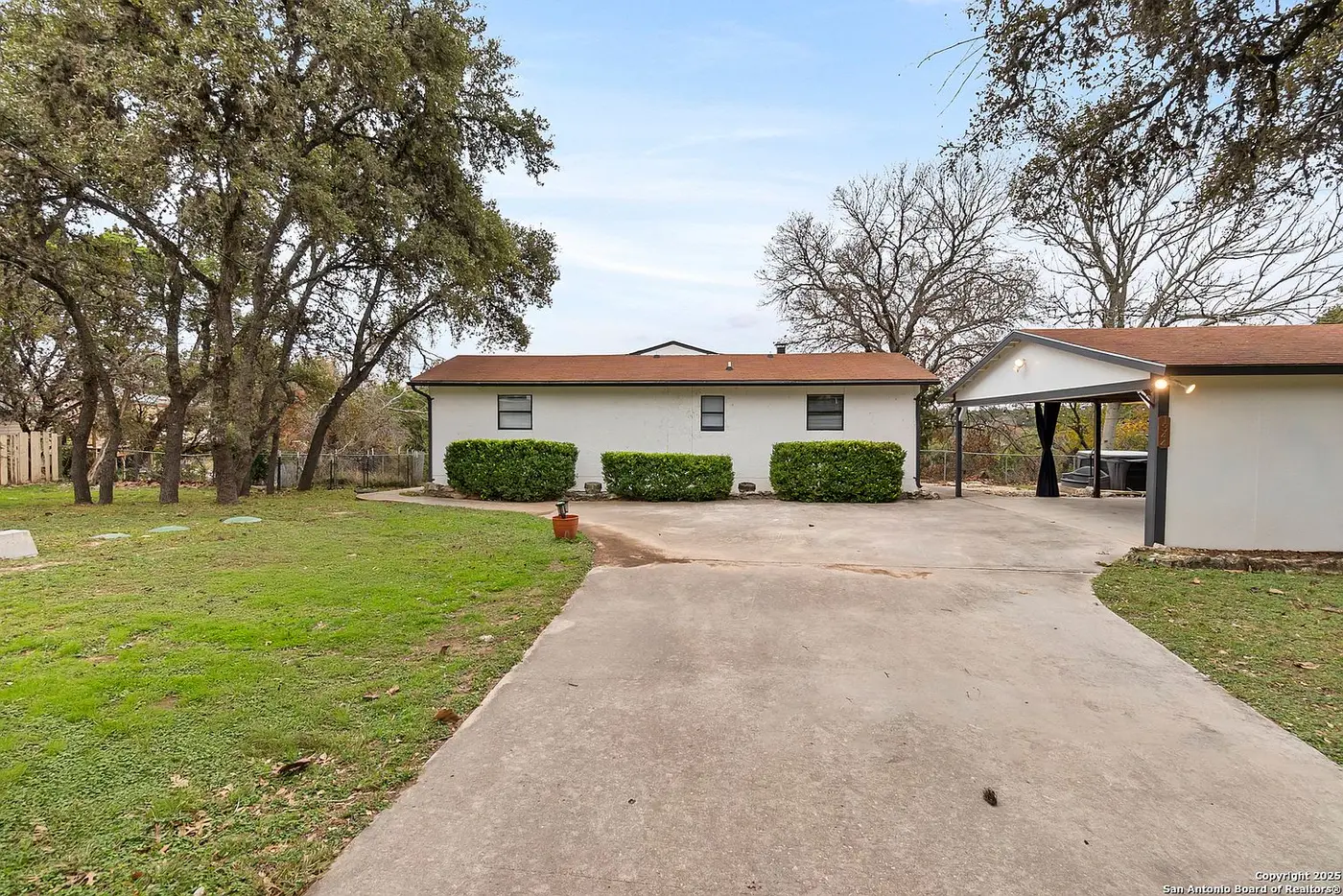 After: the same house repainted white with charcoal trim, a matching carport, and a new hot tub tucked underneath