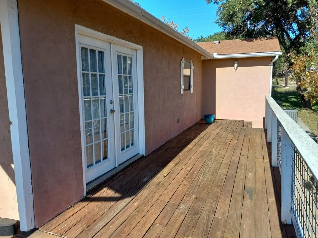Before: the tan stucco deck side of the house with French doors and original wood decking
