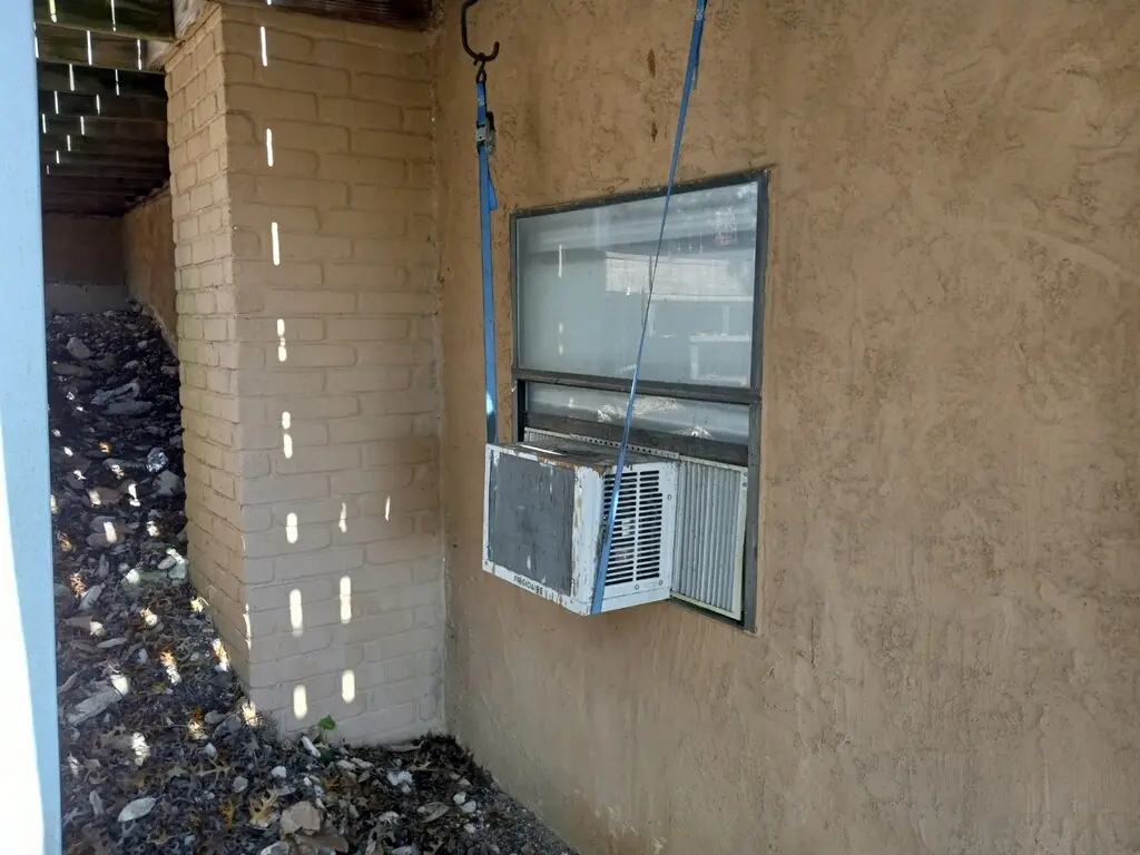Before: side of the house with an older window air conditioning unit