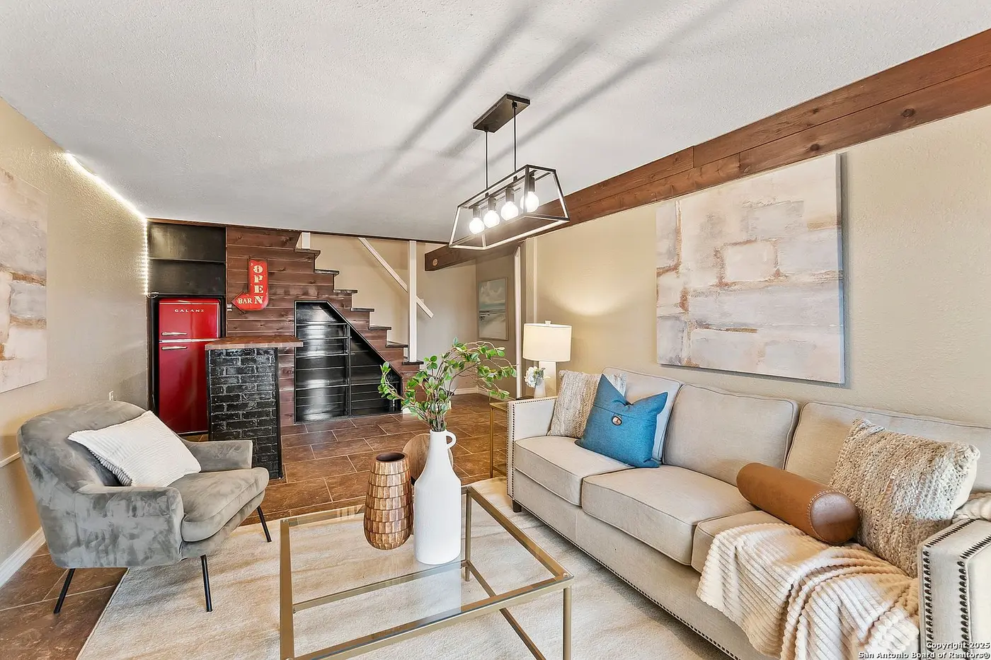 The finished lower-level lounge with a sectional, wet bar, and a staircase behind it