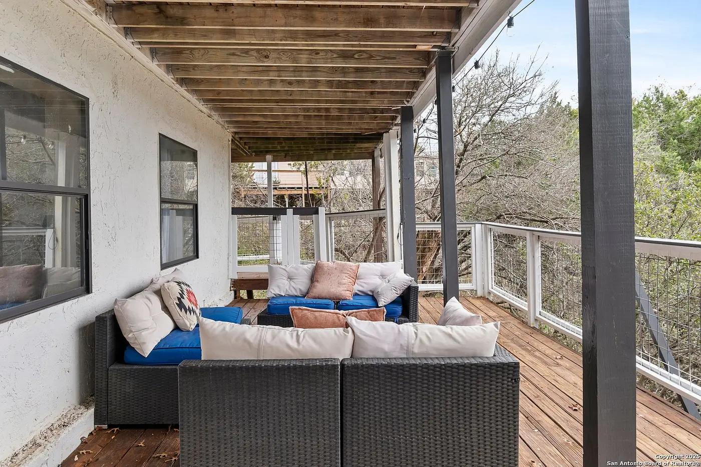 A second, covered lounge area on the lower-level patio, furnished with dark wicker seating