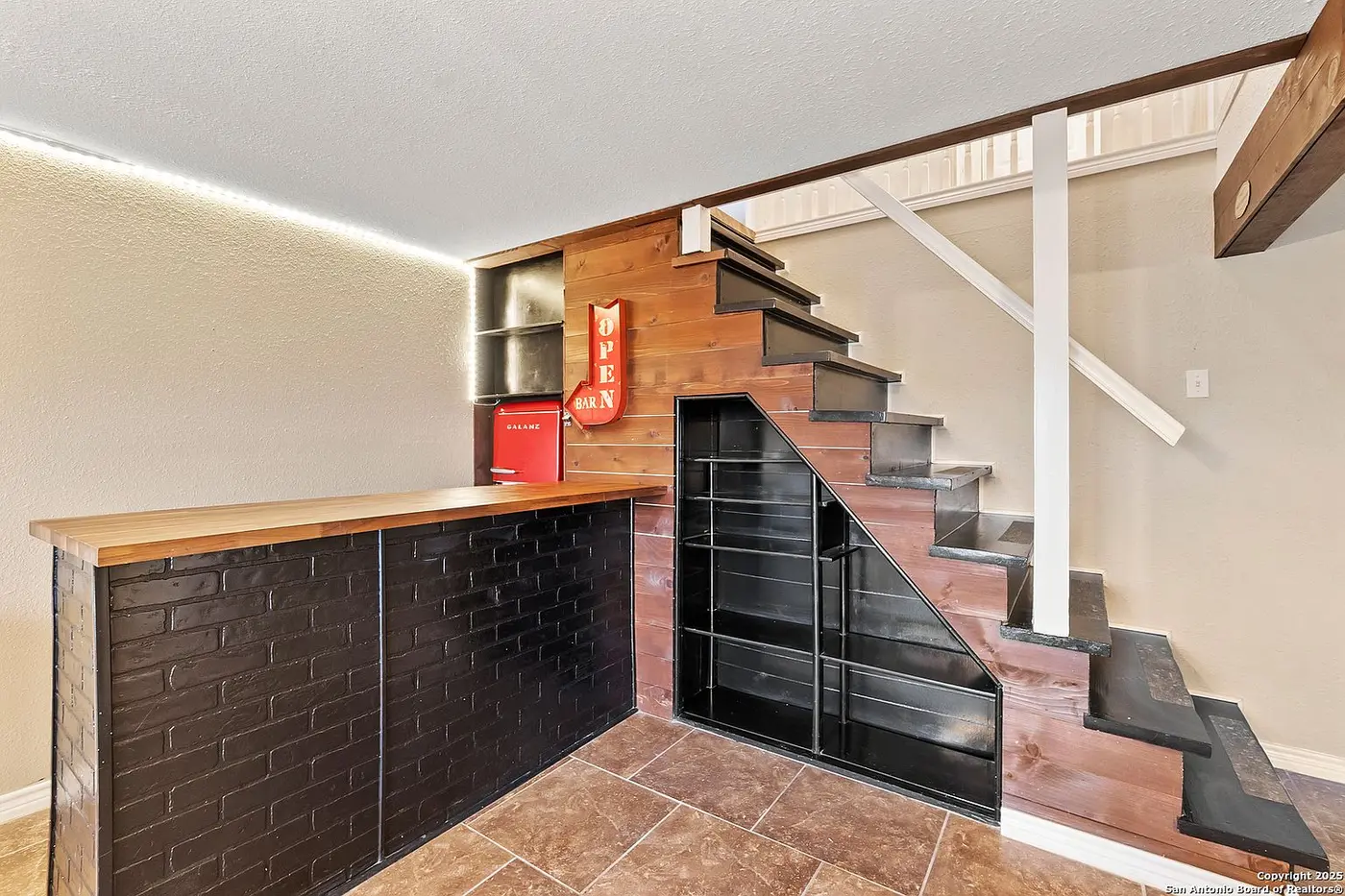 Close-up of the wet bar built into the space under the stairs, with a butcher-block counter and a retro mini fridge