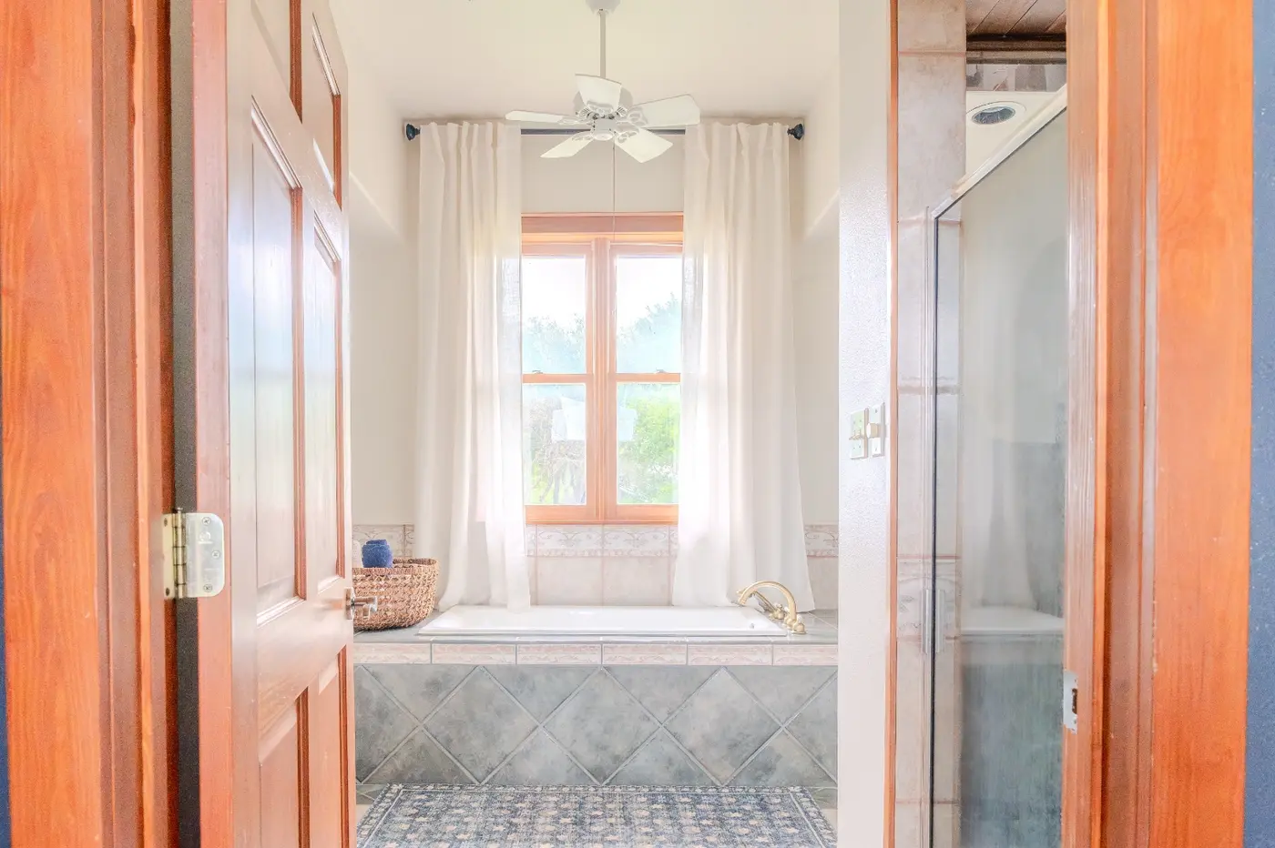 After: the same primary bathroom, now with calming beige walls and sheer curtains